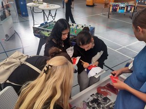 Mehrere Jugendliche füllen an einem Mitmach-Stand Quizkarten zum Thema Verhütung und sexuelle Gesundheit aus.