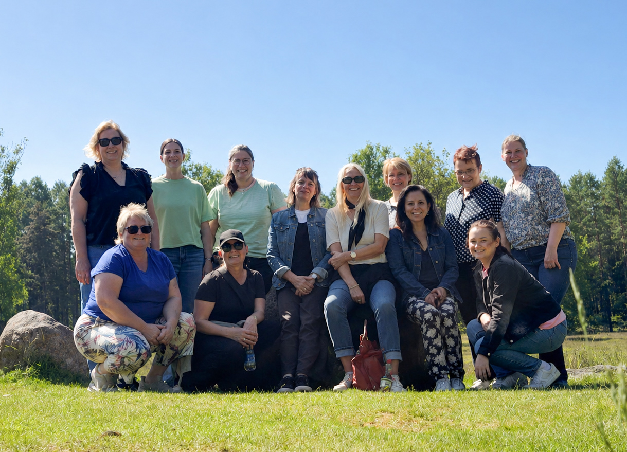 Gruppenfoto der Mitarbeitenden der Diakonie im Oldenburger Münsterland während ihres Teamausflugs in Dötlingen. Die Gruppe posiert bei sonnigem Wetter auf einer Wiese vor einer natürlichen Kulisse mit Bäumen im Hintergrund.